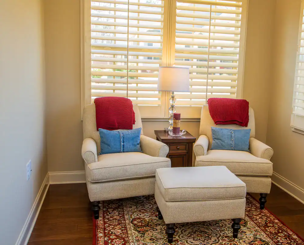 A Plus Shutters, Shades, and Barn Doors image showing stylish window blinds with cozy seating area.