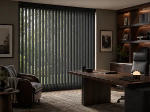 A modern office with a large desk, leather chair, shelves with books and decor, and floor-to-ceiling vertical blinds partially open to reveal greenery outside. The room has neutral colors and soft lighting.